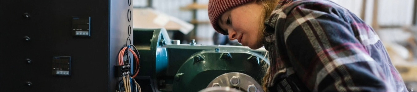 Auszubildende arbeitet in der Mechanikwerkstatt an einer Maschine