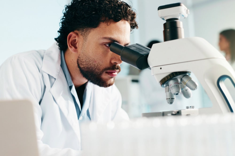 Mitarbeiter im Bereich "Sektion und Präparation" untersucht eine Probe unter einem Mikroskok