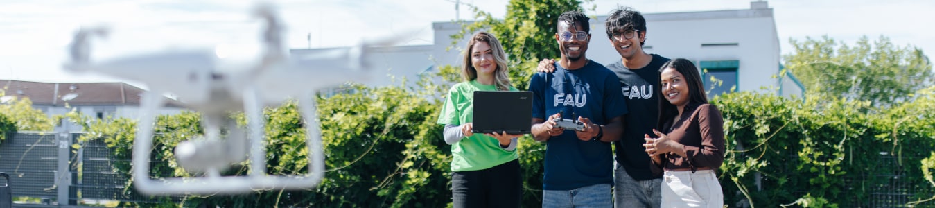 Eine Gruppe von Studierender lässt outdoor eine Drohne fliegen.
